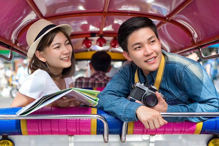 Touring Asian couple rides tuk-tuk in Bangkok
